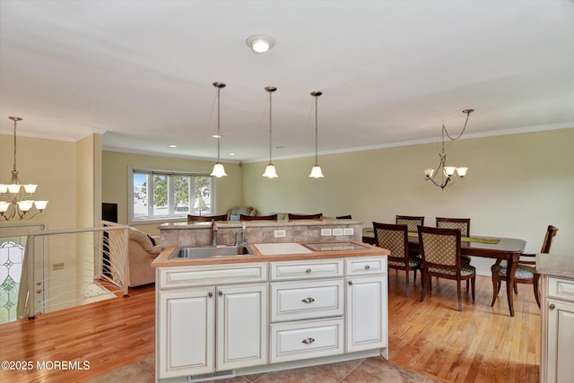 kitchen featuring an inviting chandelier, light wood-style floors, open floor plan, and a sink