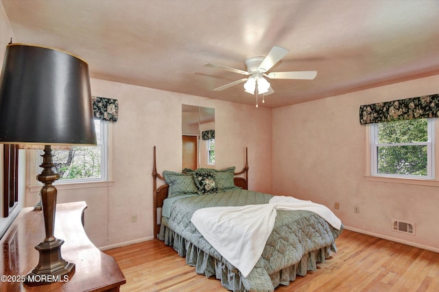 bedroom with baseboards, multiple windows, visible vents, and light wood-type flooring