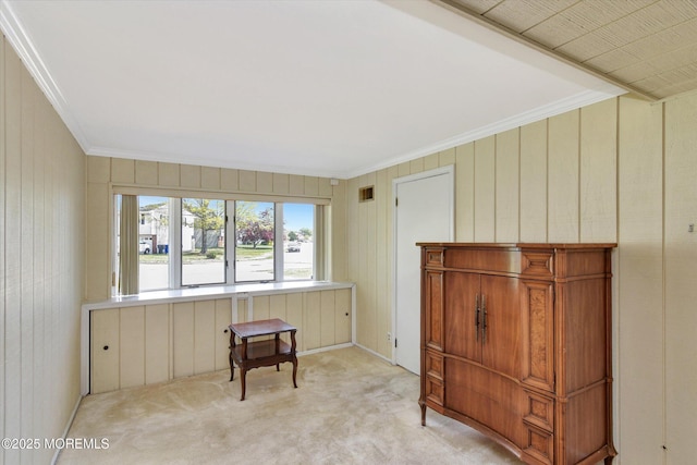 living area featuring light colored carpet, wood walls, and ornamental molding