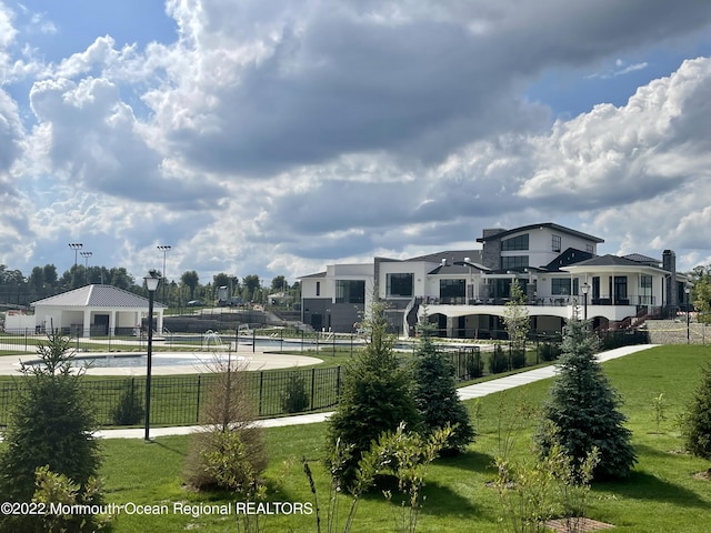 surrounding community with a lawn, fence, and a tennis court