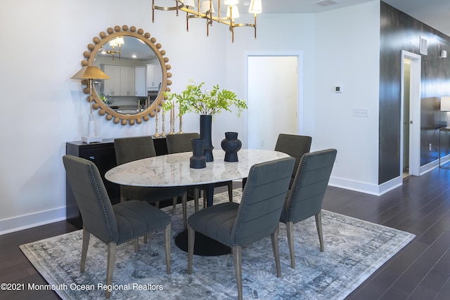 dining space featuring a chandelier, wood finished floors, baseboards, and visible vents