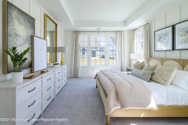 bedroom with light colored carpet, baseboards, and a raised ceiling