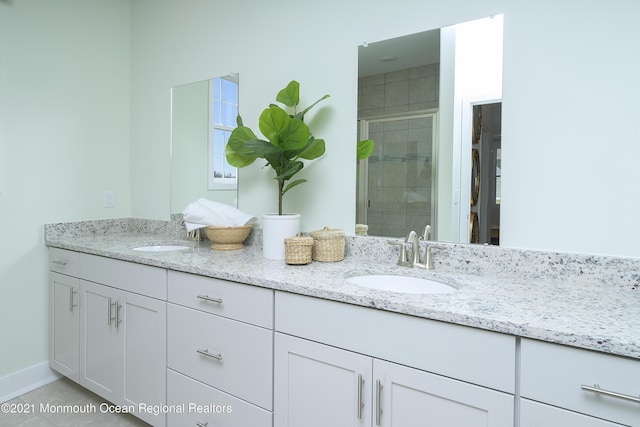 full bathroom featuring a shower stall, double vanity, and a sink