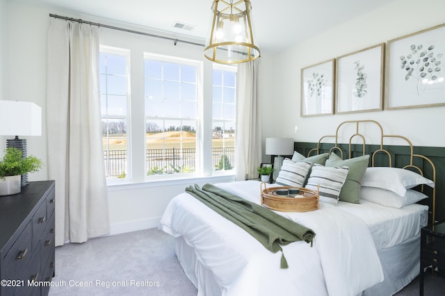 carpeted bedroom featuring an inviting chandelier and visible vents