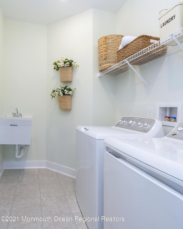 washroom featuring washing machine and dryer, laundry area, a sink, and baseboards