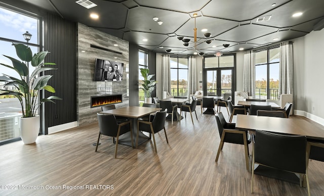 dining space featuring wood finished floors, baseboards, visible vents, and a tile fireplace