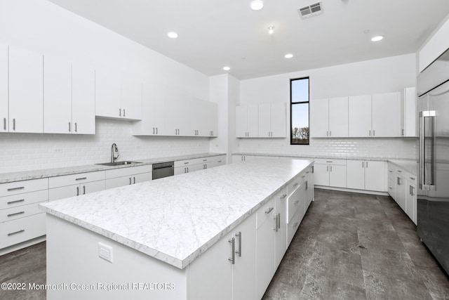 kitchen with a sink, stainless steel appliances, a large island, visible vents, and backsplash