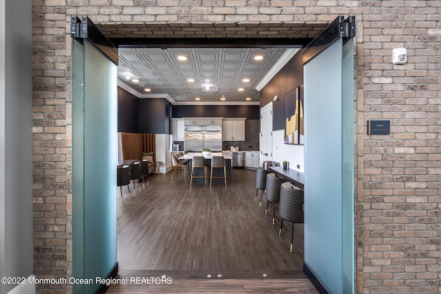 interior space featuring brick wall, dark wood-style floors, and recessed lighting