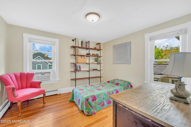 bedroom with light wood-type flooring, a baseboard radiator, and cooling unit