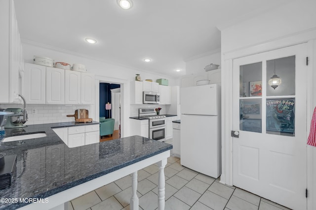 kitchen featuring freestanding refrigerator, stainless steel microwave, range with two ovens, crown molding, and decorative backsplash