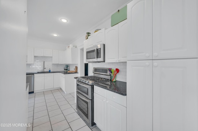 kitchen featuring stainless steel appliances, a sink, decorative backsplash, white cabinets, and light tile patterned floors