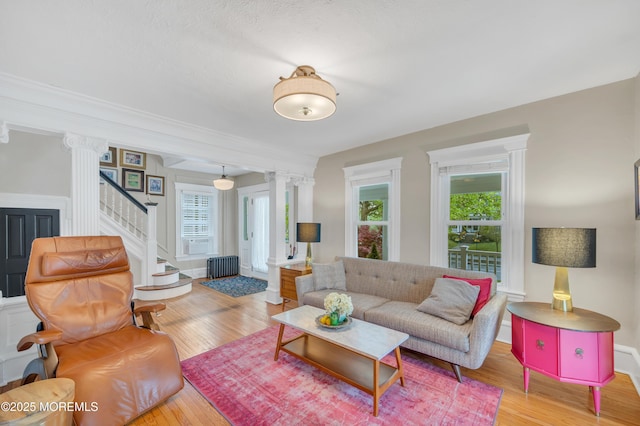 living area featuring decorative columns, radiator heating unit, and wood finished floors