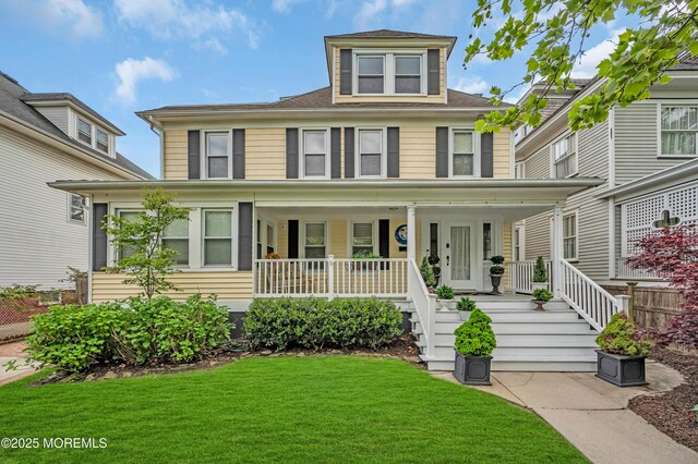american foursquare style home featuring covered porch and a front lawn