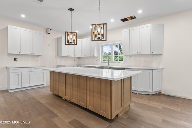38 Louise Dr, East Brunswick, NJ 08816 - kitchen featuring wood finished floors, a chandelier, light countertops, a center island, and a sink
