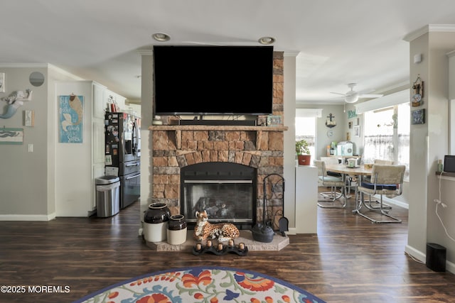 living room featuring crown molding, baseboards, wood finished floors, ceiling fan, and a fireplace