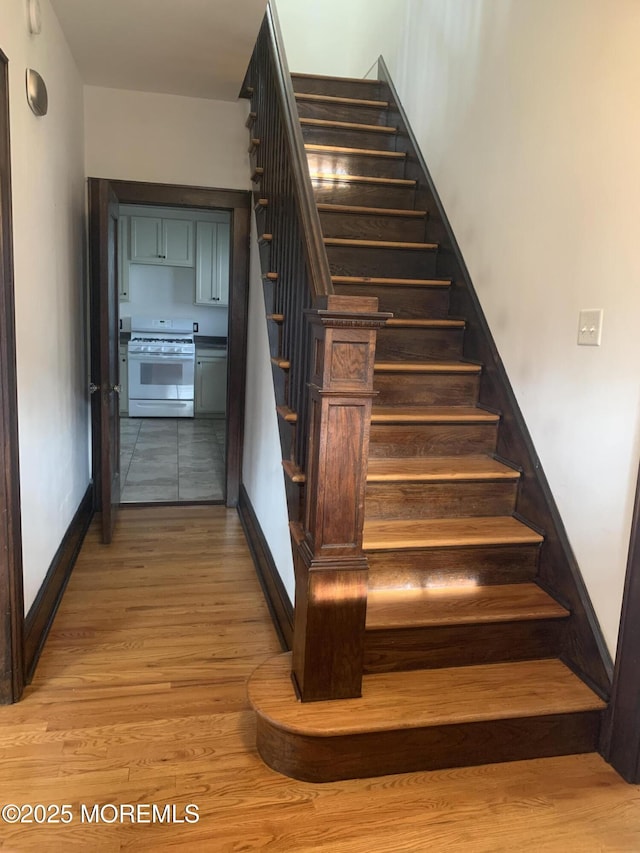 stairs with wood finished floors and baseboards