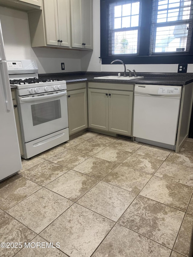 kitchen featuring white appliances, a sink, dark countertops, and gray cabinetry