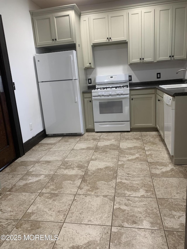 kitchen featuring white appliances, a sink, dark countertops, and baseboards