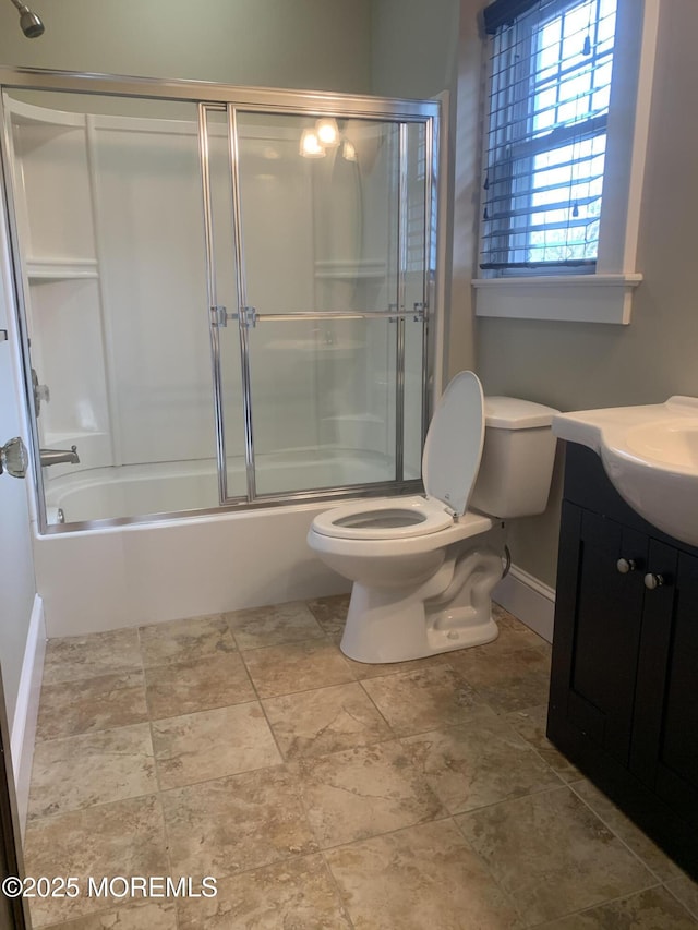 bathroom with toilet, vanity, shower / bath combination with glass door, and baseboards