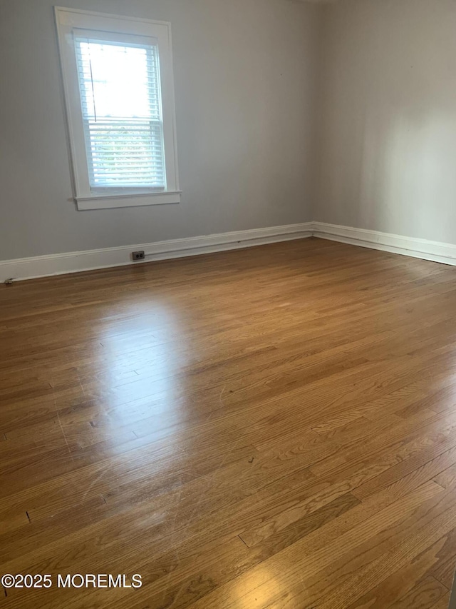 spare room with baseboards and wood finished floors
