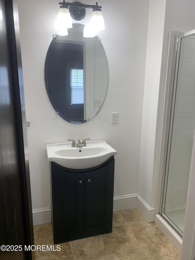 full bath featuring a stall shower, vanity, and baseboards
