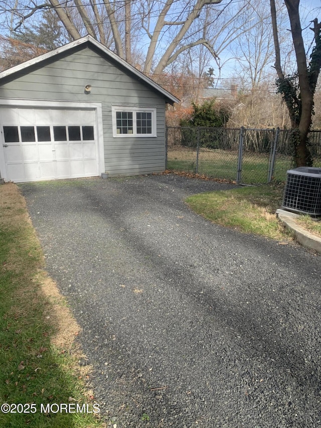 view of side of property with central AC unit, fence, an outbuilding, a detached garage, and asphalt driveway