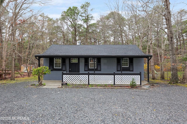 view of front of house with roof with shingles, covered porch, and fence