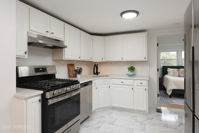 kitchen with light countertops, stainless steel appliances, a sink, and under cabinet range hood