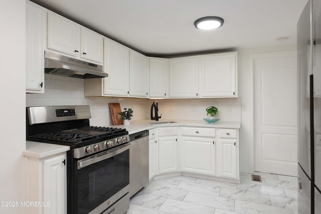 kitchen with under cabinet range hood, light countertops, stainless steel appliances, and marble finish floor