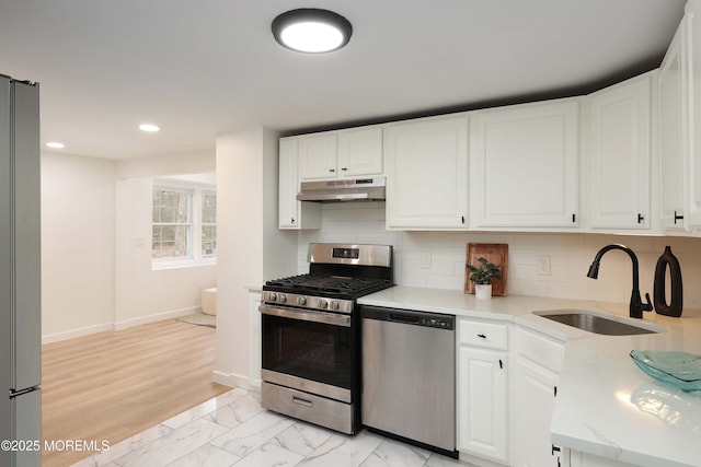 kitchen with a sink, stainless steel appliances, white cabinetry, under cabinet range hood, and recessed lighting
