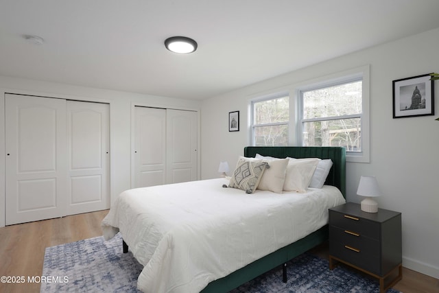 bedroom featuring two closets, wood finished floors, and baseboards