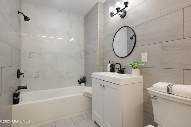 bathroom featuring toilet, washtub / shower combination, tile walls, and vanity