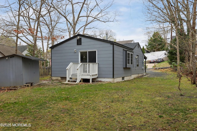 rear view of house featuring an outbuilding, roof with shingles, a lawn, and a shed