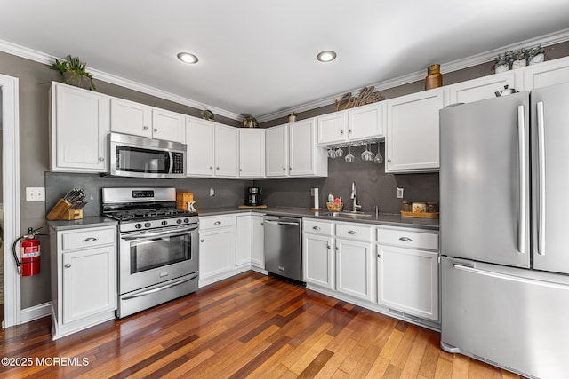 2015 Red Cedar St, Toms River, NJ 08753 - kitchen featuring stainless steel appliances, crown molding, white cabinets, dark countertops, and a sink