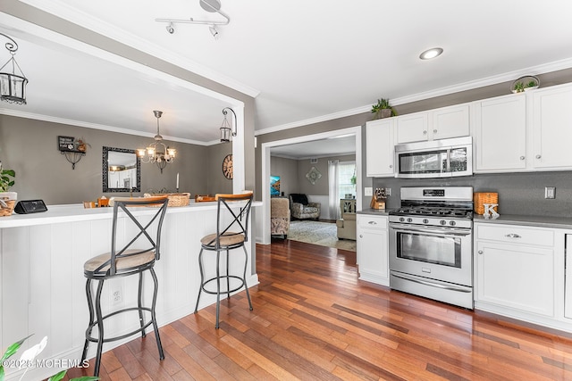 2015 Red Cedar St, Toms River, NJ 08753 - kitchen with appliances with stainless steel finishes, hardwood / wood-style floors, a kitchen breakfast bar, white cabinetry, and crown molding