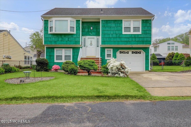 split foyer home featuring driveway, a front lawn, fence, and an attached garage