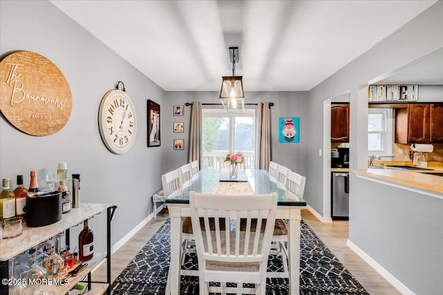 dining area with plenty of natural light, baseboards, and light wood-type flooring