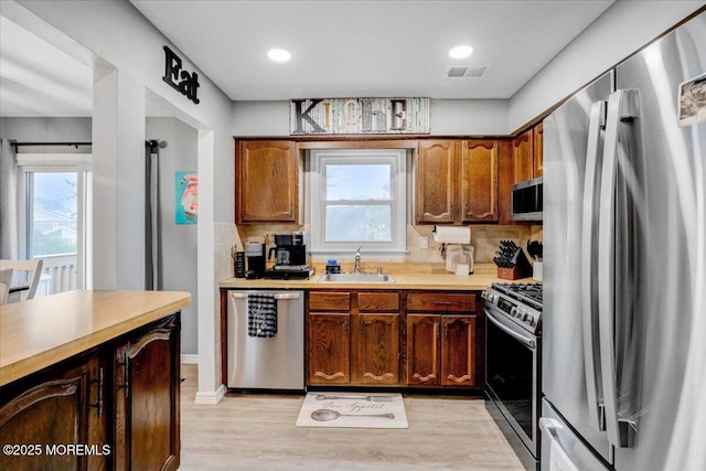 kitchen featuring backsplash, visible vents, appliances with stainless steel finishes, and a sink
