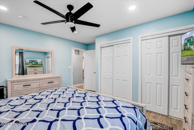 bedroom with a ceiling fan, recessed lighting, visible vents, two closets, and wood finished floors