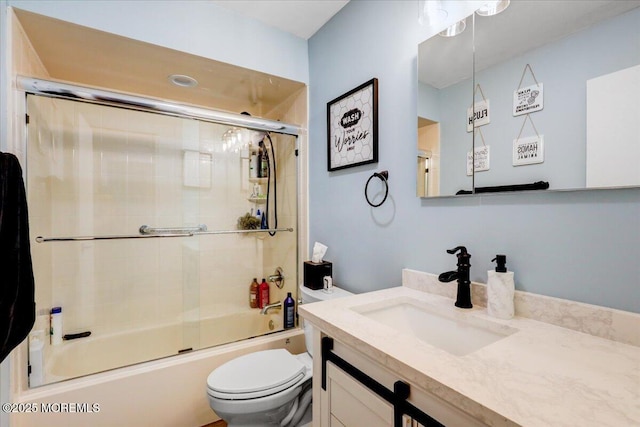 full bath with toilet, vanity, and shower / bath combination with glass door