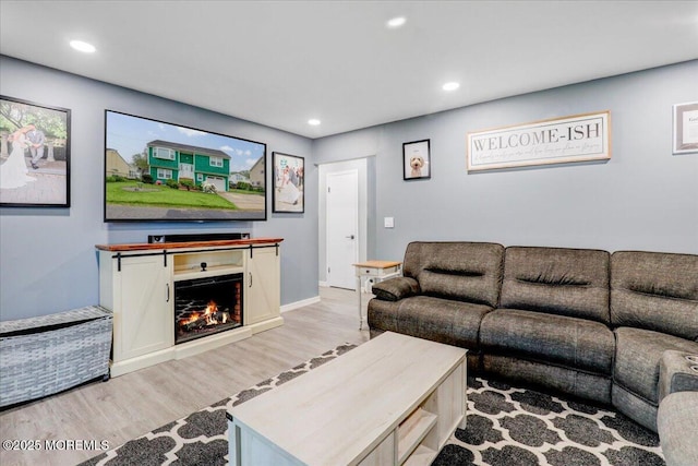 living area with light wood-style flooring, recessed lighting, and a lit fireplace