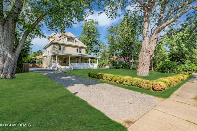 view of front of home with covered porch, aphalt driveway, and a front lawn