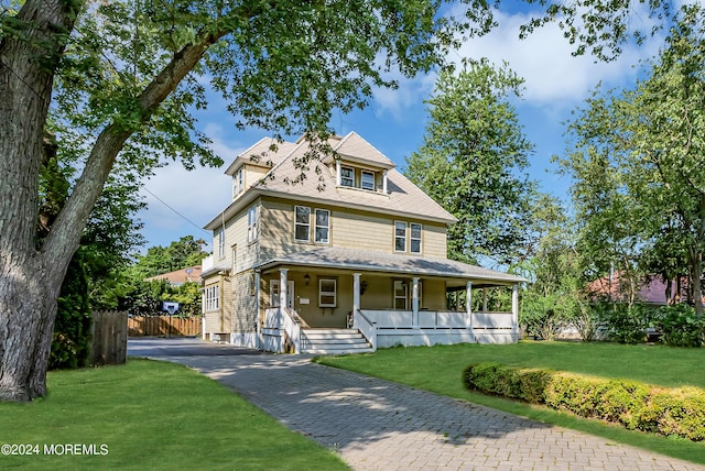 view of front of house featuring a front lawn, a porch, driveway, and fence