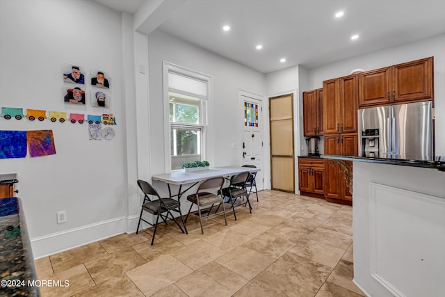 kitchen featuring recessed lighting, baseboards, stainless steel fridge, brown cabinets, and dark countertops