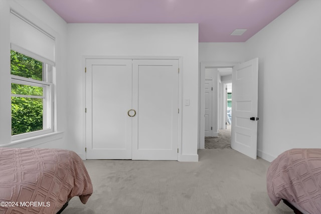 bedroom featuring baseboards, light carpet, and a closet