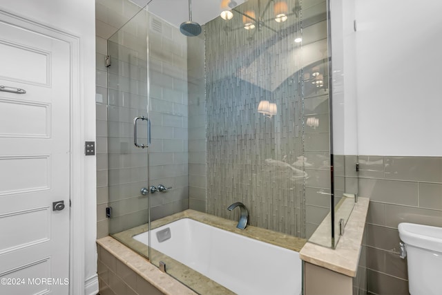 full bathroom featuring toilet, tile walls, and tiled shower / bath