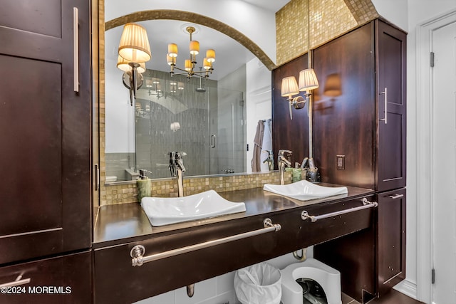 full bathroom with double vanity, a stall shower, a sink, a chandelier, and decorative backsplash