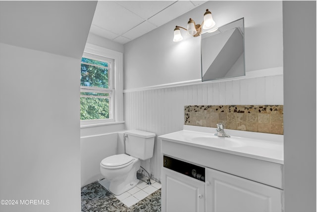 bathroom with toilet, a paneled ceiling, tile patterned floors, wainscoting, and vanity