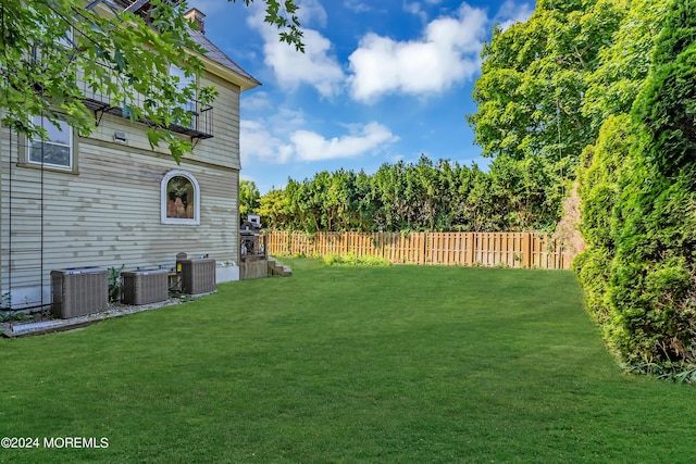 view of yard with fence and central AC