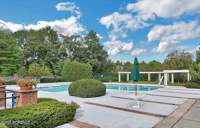community pool featuring fence, a pergola, a patio area, and view of scattered trees